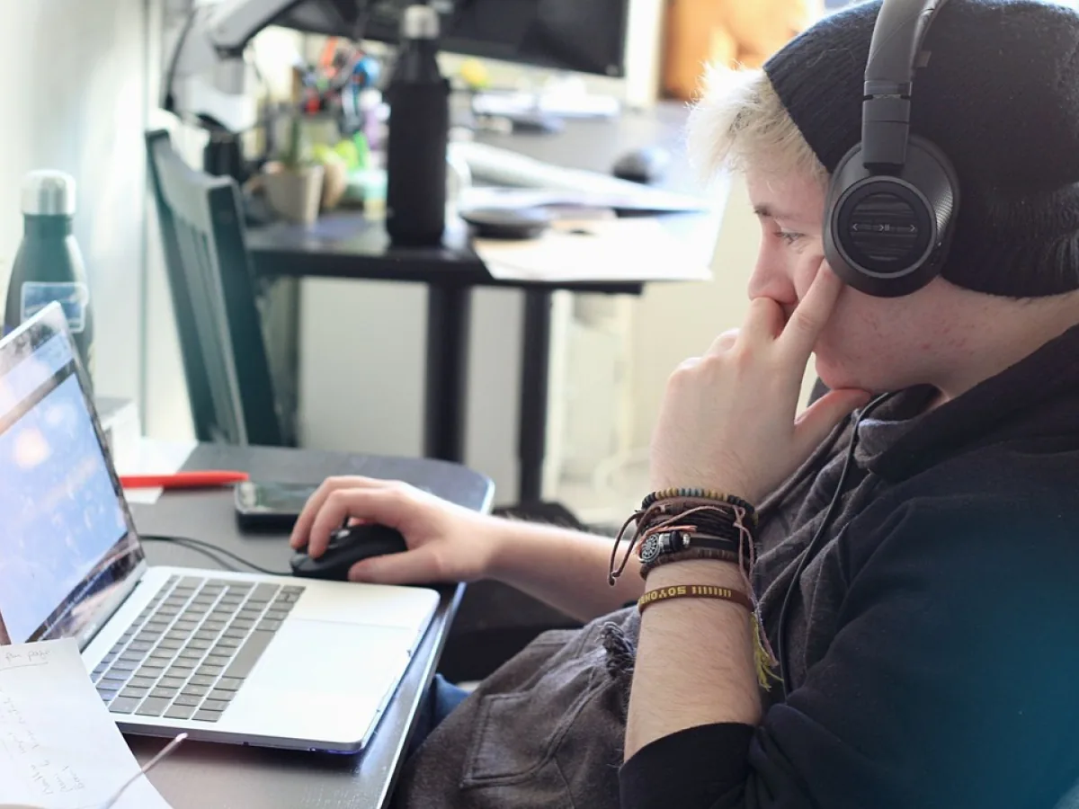 Un designer concentré devant son ordinateur portable, casque sur les oreilles.